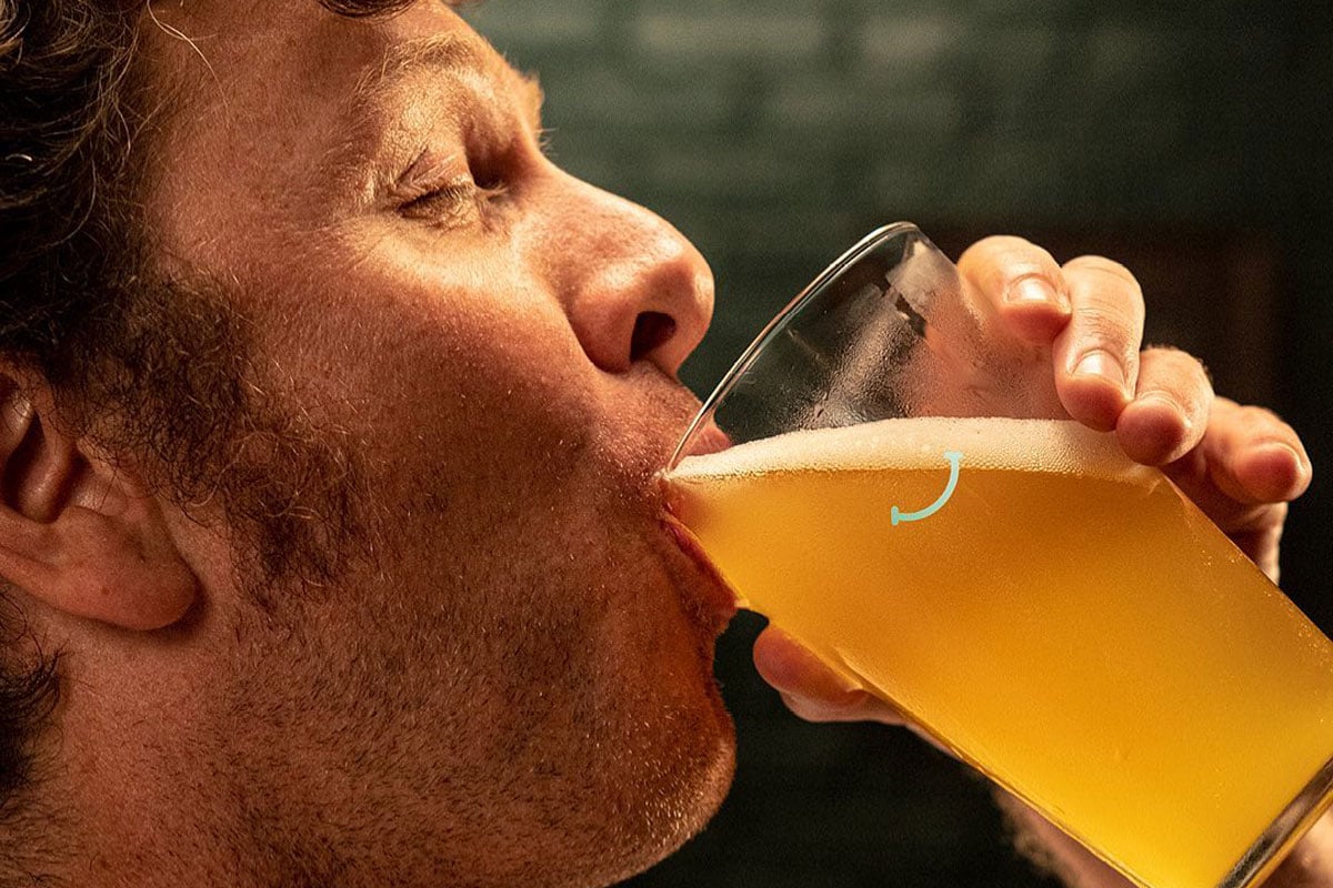 Person savoring frothy beer in focus.