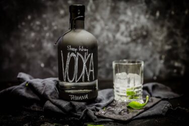 Sheep Whey Vodka bottle beside icy lime glass.