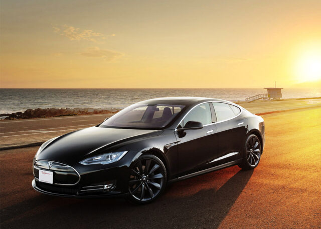 Tesla Model S in sunset glow by ocean.
