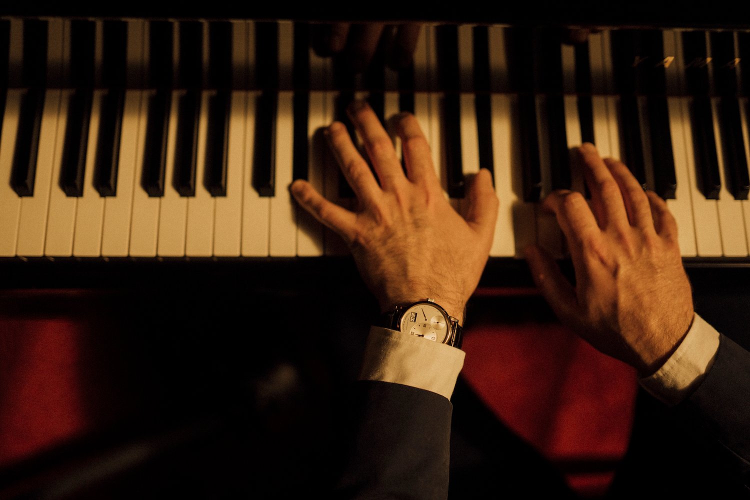 Pianist wears Swiss watch; elegance in harmony.